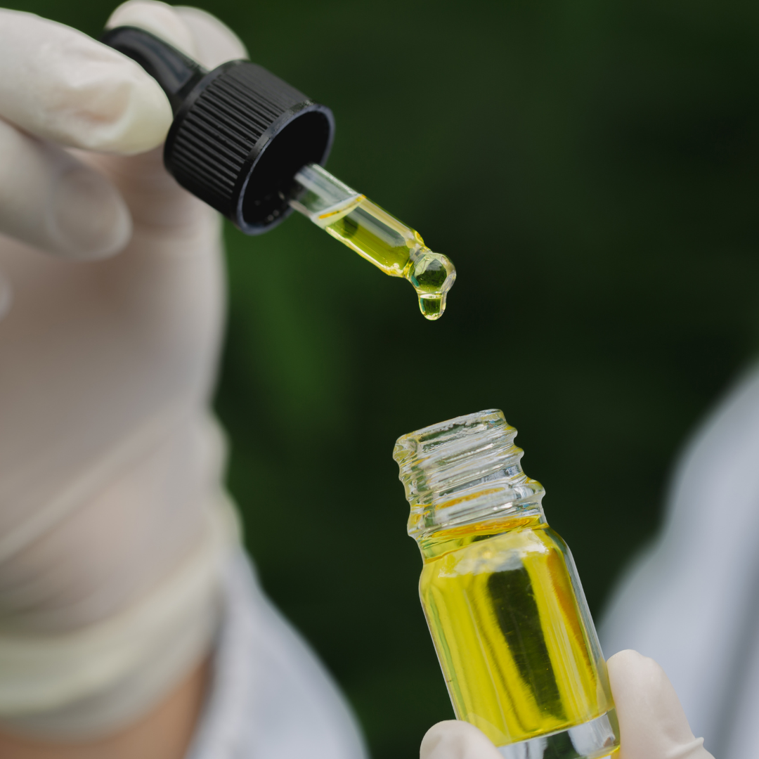 Conta-gotas aplicando óleo medicinal em um frasco, com estetoscópio ao fundo.